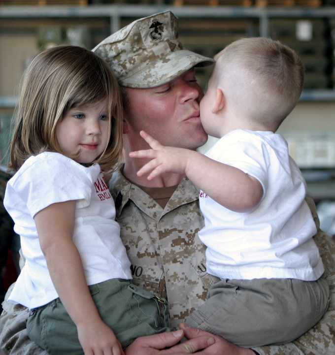 A US soldier holds his daughter and his son.