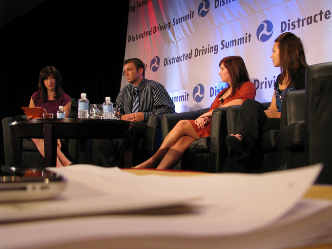 A picture of four panelists sitting at a small table. One panelist is talking while the others listen.