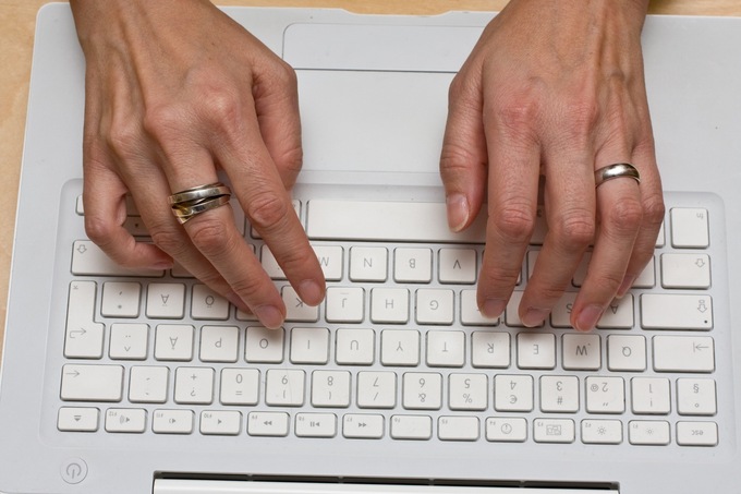 A photo of a woman's hands on a computer keyboard.