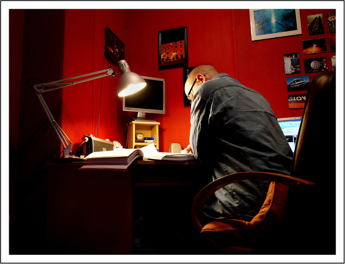 A picture of a man sitting at a desk and reviewing research material.