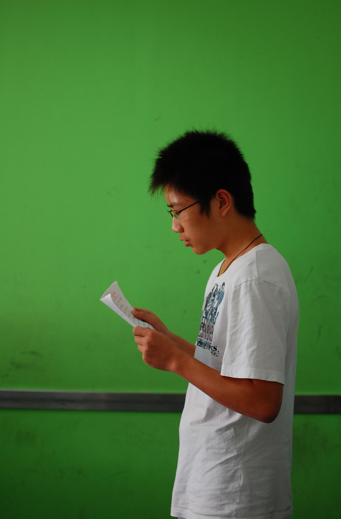 A picture of a man holding a piece of paper and practicing his speech.