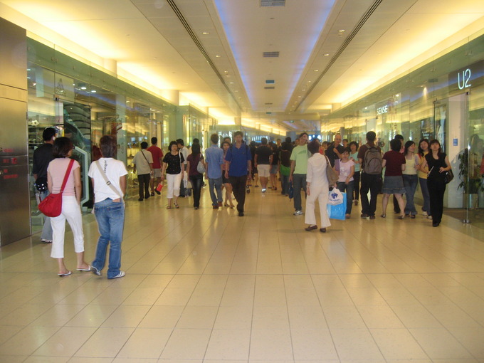 people walking around the hall of a shopping mall with stores around