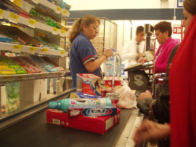 A woman scans the items in a populated grocery store line
