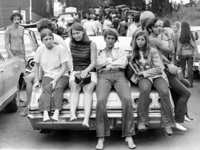Young men and women sitting on the trunk of a car