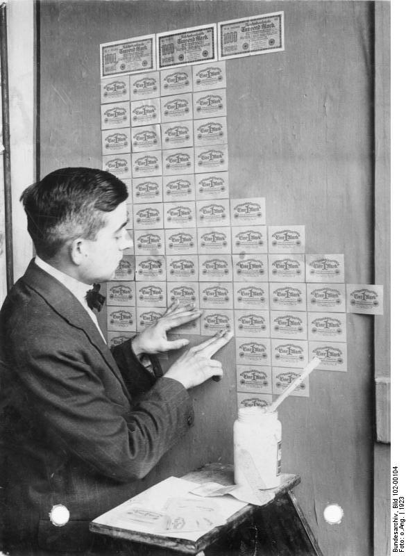A young german man plasters a wall with bank notes