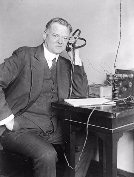 Photograph of Herbert Clark Hoover listening to a radio