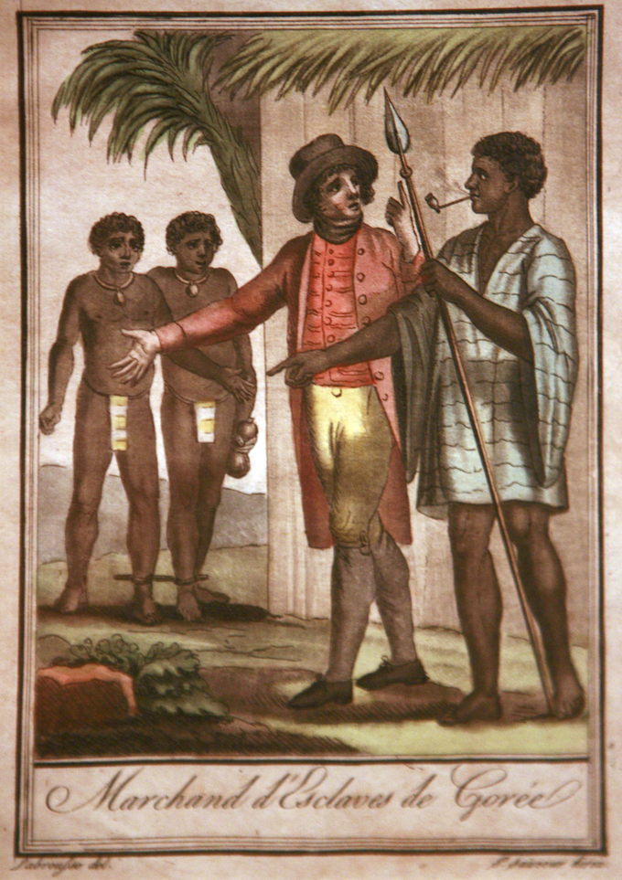 The drawing depicts a European slave trader and an African slave trader discussing the sale of two male slaves who are standing in the background. The slaves' feet are shackled together.