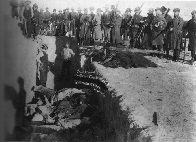 Burial of the dead after the massacre of Wounded Knee. U.S. Soldiers putting Native Americans in a common grave; some corpses are frozen in different positions