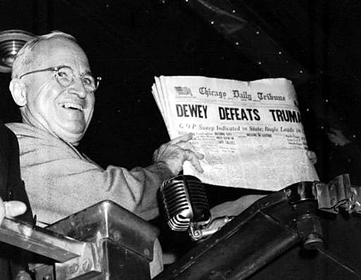 Truman smiles as he holds up the newspaper with the incorrect headline.