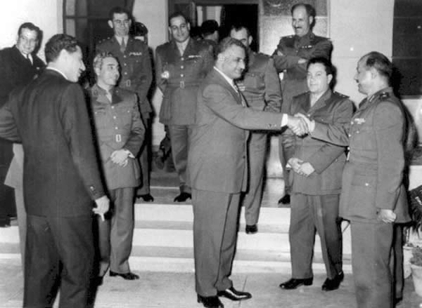 Photo of Nasser shaking hands with al-Bizri surrounded by a Syrian delegation.