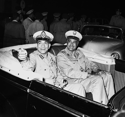 Photo of Prime Minister Gamal Abdel Nasser (right) and President Muhammad Naguib (right) in an open-top automobile during celebrations marking the second anniversary of the Egyptian Revolution of 1952.