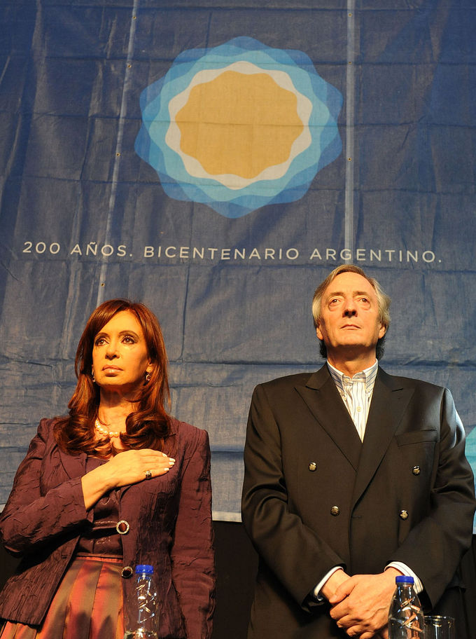 Photo of Cristina Fernández and Néstor Kirchner during the Bicentenario. She is standing on the left, holding her hand to her chest, he is standing next to her, hands folded in front of him.