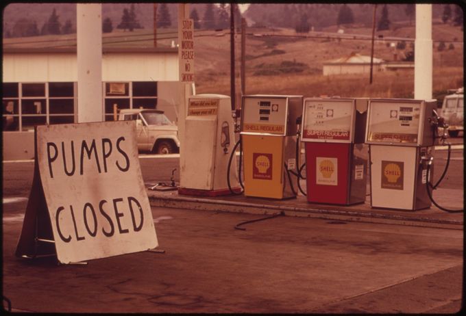 A photo of a gas station in 1973 with a sign next to the pumps saying 