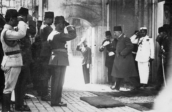 Photo of Mehmed VI, the last Sultan of the Ottoman Empire, leaving the country after the abolition of the Ottoman sultanate, 17 November 1922. He is walking through an archway surrounded by saluting soldiers.