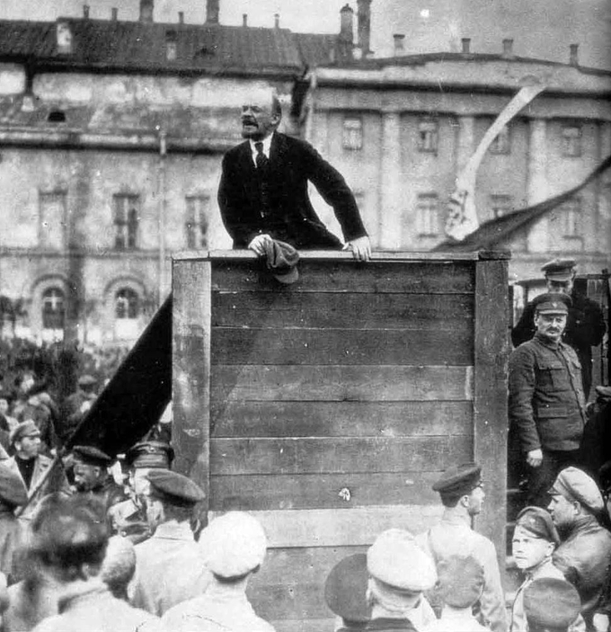 Photo of Vladimir Lenin speaking at a raised podium to a crowd of people.