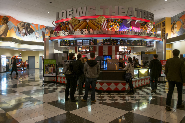 Photo of people standing in line at a concession stand in a Loews Theatre