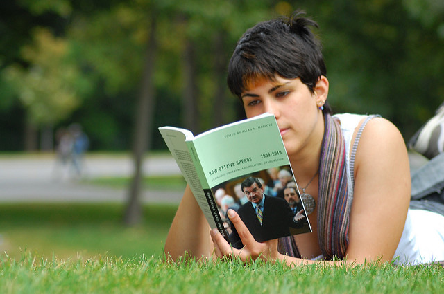 Photo of woman lying on grass, reading 
