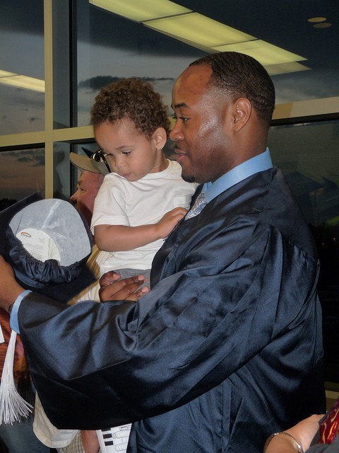 Man in graduation gown holding child