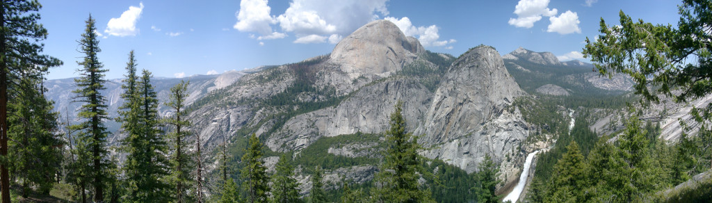 A panoramic shot of half dome and the rock formations that surround it. The massive formations curve and rise as mountains.