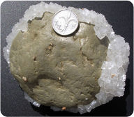 A coin on top of a gray stone embedded in white crystals