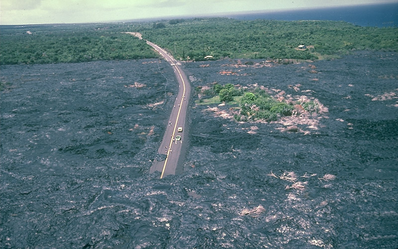 Highway completely surrounded and partially covered with lava. The lava stretches for at least a mile on every side.