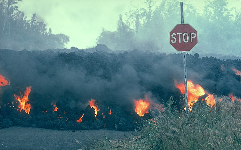 Lava flow with visible fire moving behind a stop sign.