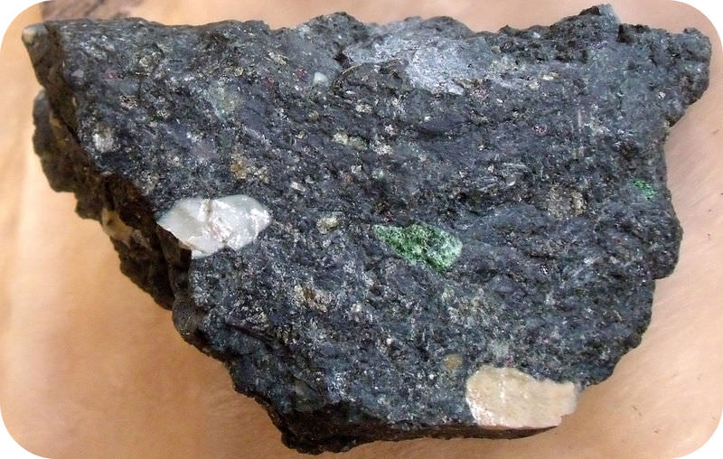 A rough dark rock with diamonds embedded in it