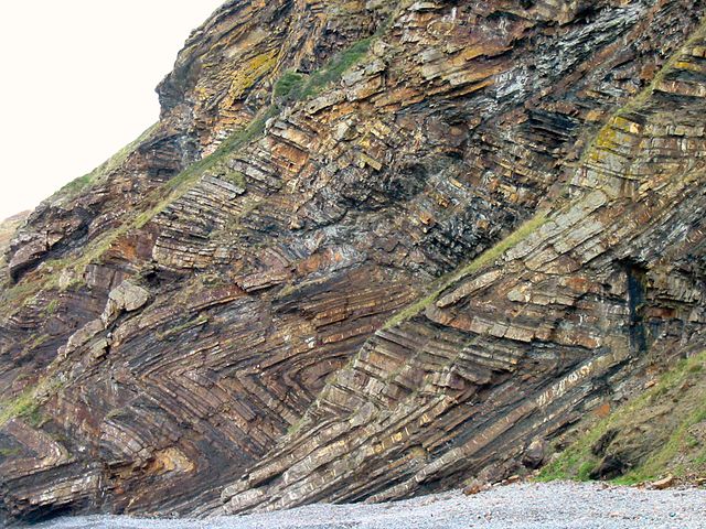 Rock face with chevron patterns of sedimentary layers.