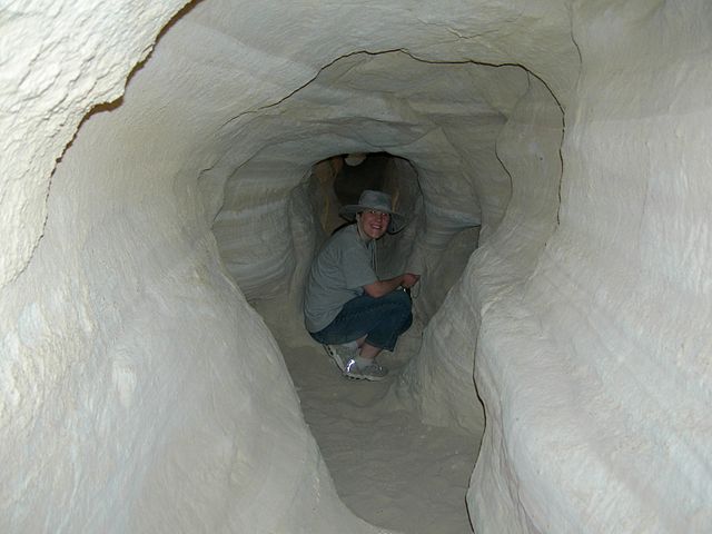 Woman crouching in the mine; The tunnel is only big enough for her to crouch.