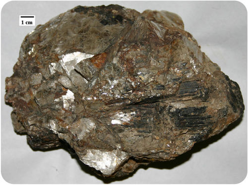 Figure 2. A pegmatite from South Dakota with crystals of lepidolite, tourmaline, and quartz (1 cm scale on the upper left).