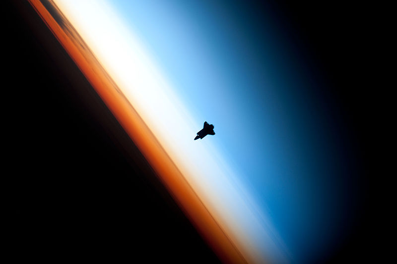 Photograph taken from space of the Earth's surface and layers. The orange layer is the troposphere, where all of the weather and clouds which we typically watch and experience are generated and contained. This orange layer gives way to the whitish Stratosphere and then into the Mesosphere. In some frames the black color is part of a window frame rather than the blackness of space.