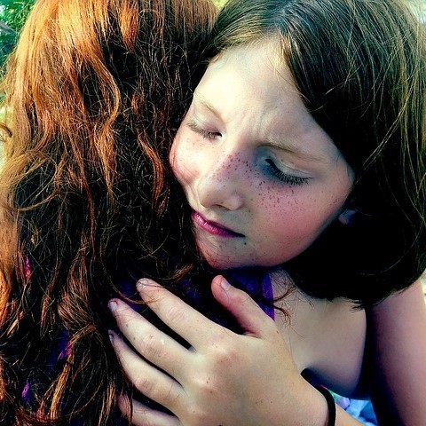 A girl closes her eyes as she hugs her friend. [Image: CC0 Public Domain, https://goo.gl/m25gce]