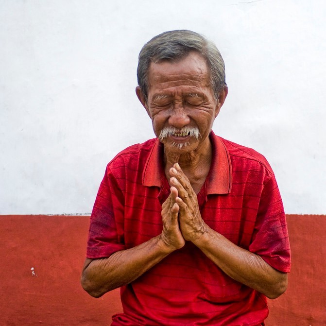 A man closes his eyes and puts his palms together in front of his heart as a symbol of gratitude. [Image: Trey Ratcliff, https://goo.gl/MKJUCl, CC BY-NC-SA 2.0, https://goo.gl/Toc0ZF]