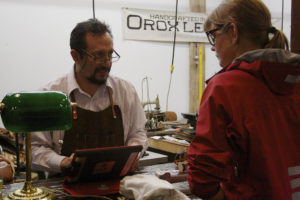 The owner of Orox Leather in his shop, photographed behind the counter, helping a female customer