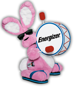 A stuffed pink bunny wearing sunglasses and beating a drum.