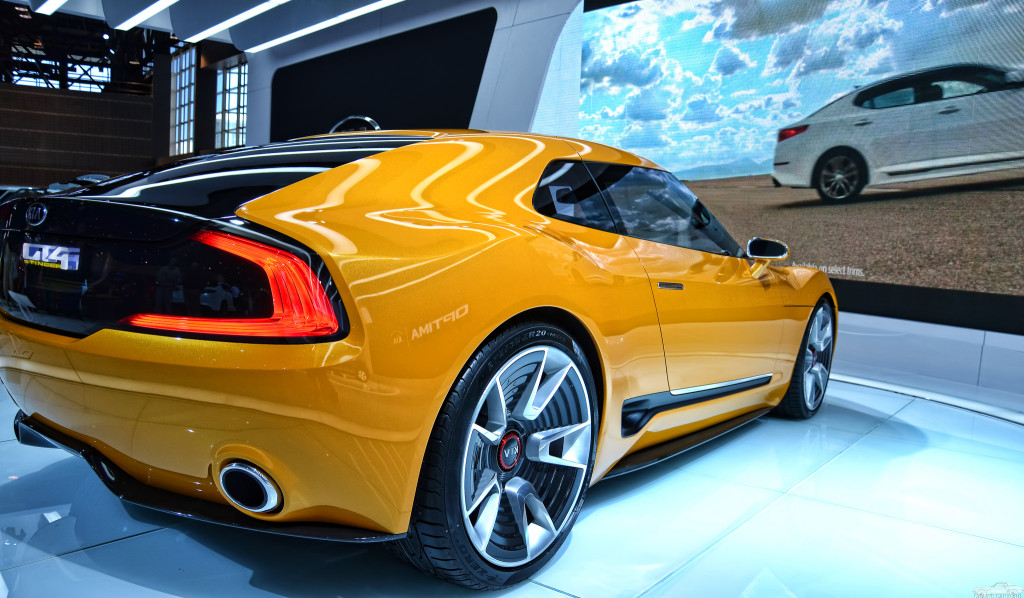 Photo of a yellow KIA GT4 Stinger sports car in a show room.