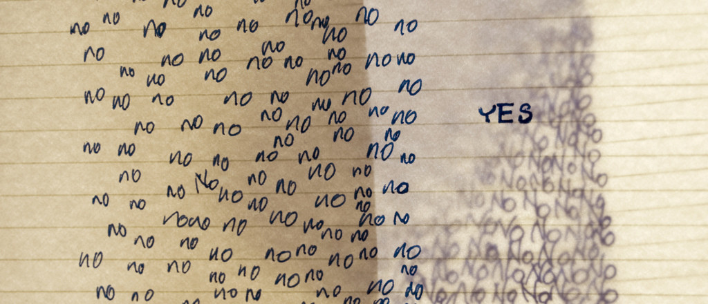 Lined notebook paper with the word NO written repeatedly on the left; on the right is the single word YES.