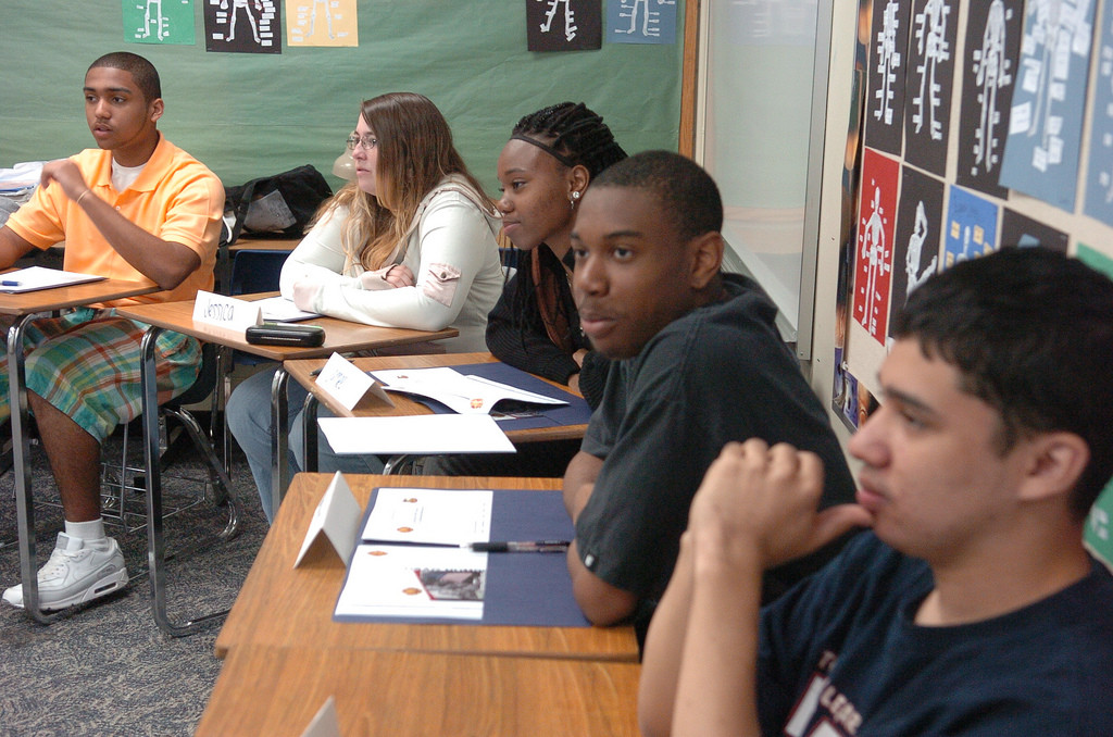 A group of students at desks listening.