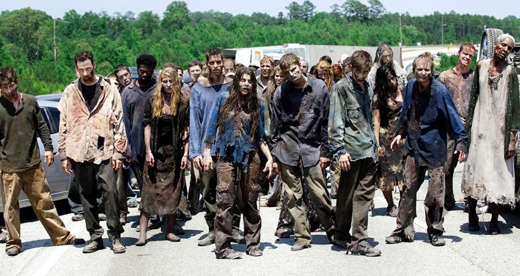 A gathering of people dressed as zombies, complete with bloody and torn clothes, scarred faces, and vacant expressions.