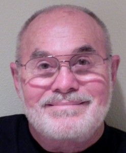 Smiling headshot of 60-year old man with white beard and glasses