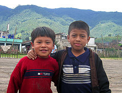 Two boys smiling outside of what appears to be their village school.