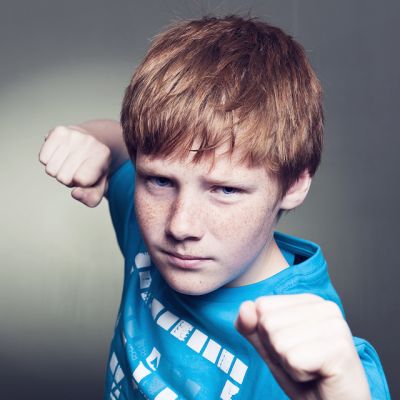 Young teenager holding his fists out ready to punch the photographer.