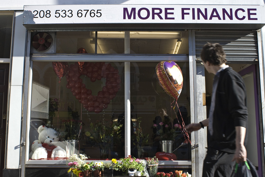 A young man walks by a shop window. A sign at the top, which has a phone number and reads,