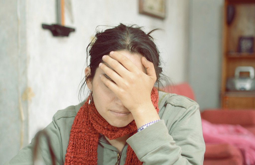 A photo of a distraught woman with her hand over her face.