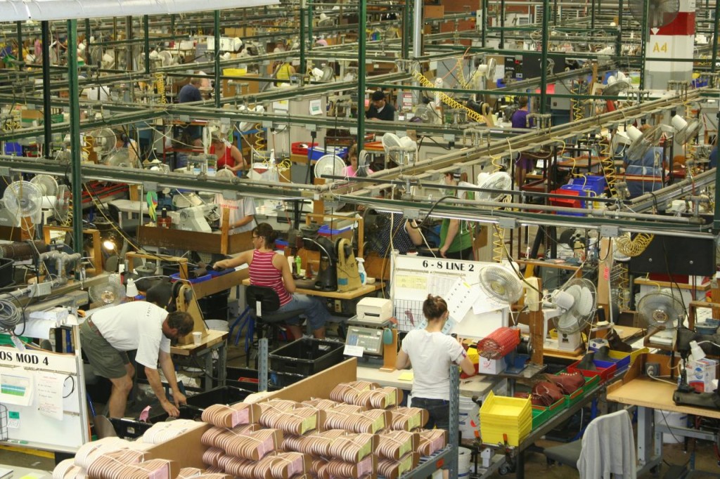 Photograph of factory workers for a shoe company working separately on individualized tasks.