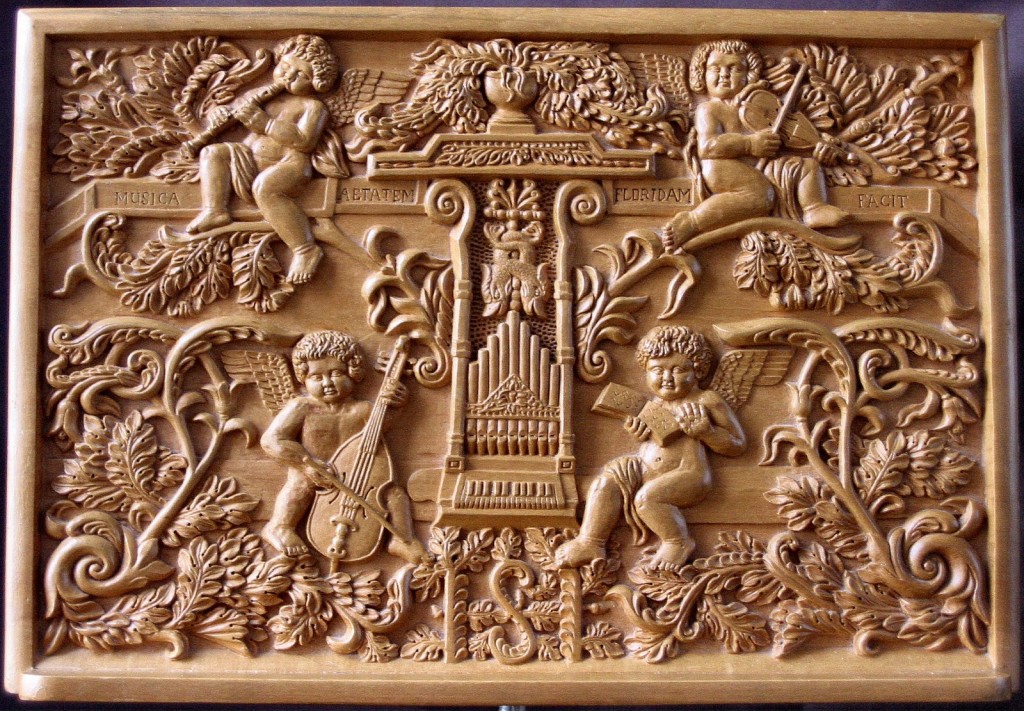 Wood carving showing four angels playing instruments: violins, viola da gamba, and the recorder 