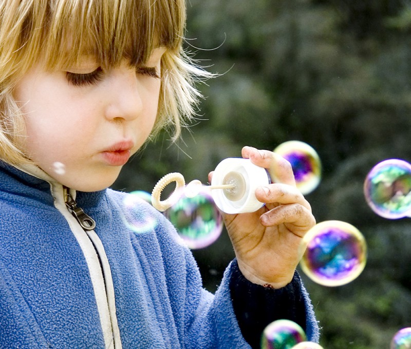 The soap bubbles that the child blows into the air maintain their shape because of the attractive force between the molecules of the soap bubble.