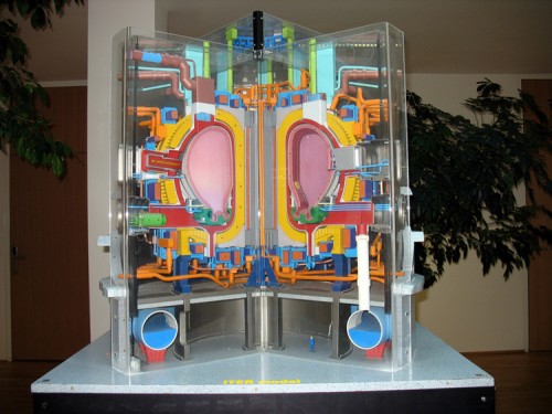 A three-dimensional cut-away model showing the interior of a complex technical device. The device has a central cavity and there are many tubes and connectors arranged around the central cavity.
