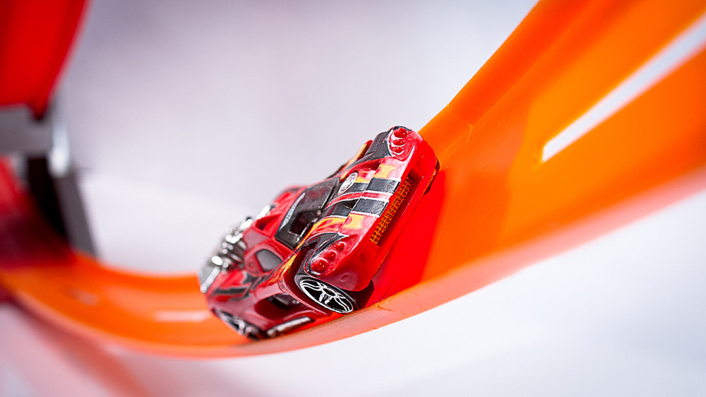 A toy car is moving up a curved track.
