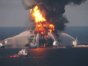 Small ships blast water at an oil rig that is on fire.